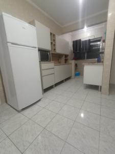 a kitchen with white appliances and a white tile floor at Vila Caiçara 80 metros da praia in Praia Grande +19 photos