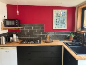 a kitchen with a stove and a red wall at Au beau frêne - Gîte in Beauregard