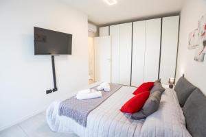 a bedroom with a bed with red pillows and a flat screen tv at Le Ninfee in Zola Predosa