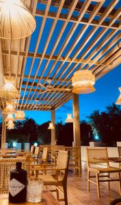 un patio con sedie, tavoli e lampadari a braccio di Zante Pantheon Hotel a Tsilivi