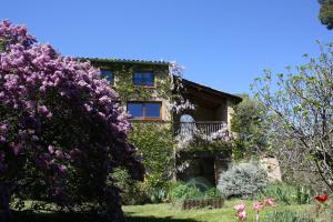 an old house with purple flowers in front of it at Gite rural de Bergnes à l'ombre des grands pins in Campagne-sur-Aude
