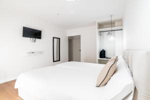 a white bedroom with a bed and a flat screen tv at Casa Jazmin by Blossom Hotels in Granada +58 photos