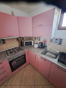 a small kitchen with pink cabinets and a sink at Casa Doi Crai in Zărneşti +36 photos
