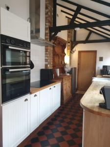 a kitchen with white cabinets and a black appliance at St Cuthbert's Keep in Bedford