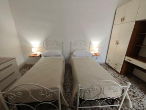 two beds in a small room with two lamps at Dimora Sciroccu e Tramuntana in Taviano