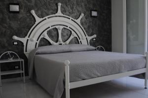 1 dormitorio con cama blanca y cabecero de madera en Badinomare, en Terracina