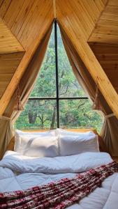 デヘラードゥーンにあるThe Brookside Bungalowの大きな窓のある部屋のベッド