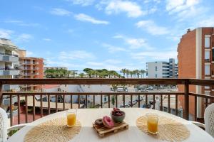 Una mesa con dos vasos de jugo de naranja en un balcón. en Apartamento TECAVI II, en La Pineda