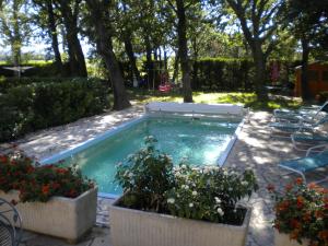 a swimming pool with a bench and some plants at Logis du Comte in Suze-la-Rousse