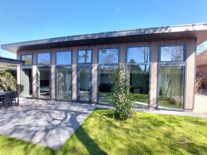 a house with glass windows and a lawn at Comfort bungalow 02 in Putten