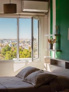 a bedroom with a bed and a large window at Dolce Casa Departamentos in Neuquén +43 photos