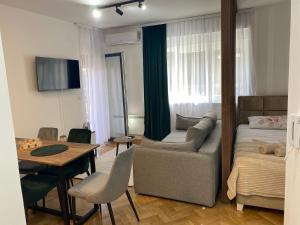 a living room with a bed and a couch and a table at Apartman MM Vrnjacka Banja in Vrnjci