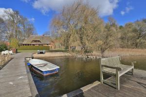 a boat on the water next to a bench on a dock at Fischerhaus Whg Abendrot in Neukloster
