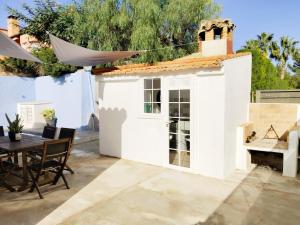ein kleines weißes Haus mit einem Tisch und Stühlen in der Unterkunft Casa Robles, casa con piscina y barbacoa in Partida de La Cañada