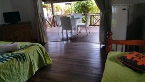 a room with a wooden floor and a balcony with a table at Pension de famille HITI MOANA VILLA in Papara