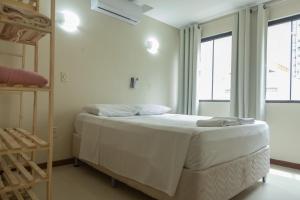 a white bedroom with a bed and two windows at HANNA Balneário Hotel in Balneário Camboriú