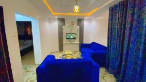 a living room with blue couches and a tv at The Diamond Boho Apartment in Ibadan