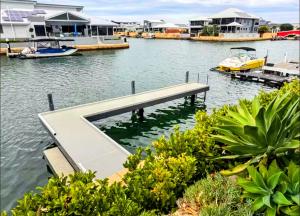 a house on the water with a dock and boats at Mariners Cove Luxury Canal Home in Mandurah