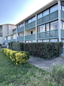 un edificio con una siepe di fronte a un edificio di Jolie T2 avec terrasse proche plage a Soulac-sur-Mer
