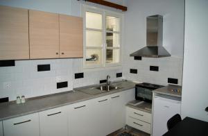uma cozinha com armários brancos, um lavatório e uma janela em Kathopouli Apartment in Ilha de Rhodes