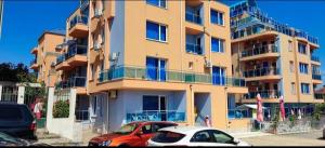 a large building with cars parked in front of it at Лукс Апартамент Морска Перла in Primorsko