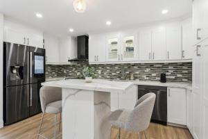 a kitchen with white cabinets and a counter with chairs at Urban Nest Home 4bed 4bath Parking Baby Crib in Mississauga