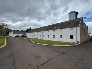 an old white barn with a tower on a street at Willowbarn Rafford Self Catering in Forres