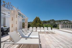 a row of white lounge chairs on a patio at Villa Stellina in Ostuni