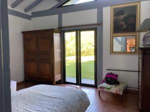 a bedroom with a bed and sliding glass doors at maison dans les landes avec piscine in Trensacq