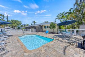 a swimming pool with patio furniture and umbrellas at Sandy Cabana - 1104N in Siesta Key