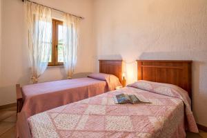 a bedroom with two beds and a window at Casa Valeria Costa Paradiso in Li Valcaggi