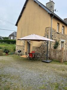 a table with an umbrella in front of a building at Maison normande tout confort in Saint-Michel-de-la-Pierre