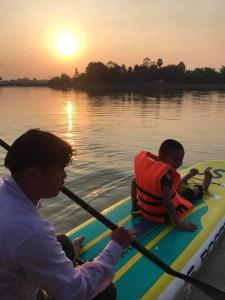 two people on a paddle board in the water at เอสบีพูลวิลล่า in Amphoe Phon Thong
