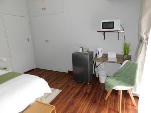 a bedroom with a bed and a desk with a microwave at Tanya's Haven Guesthouse in Klerksdorp