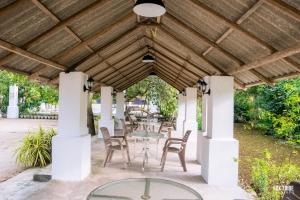 a wooden pergola with chairs and a table under it at Riverside Hotel Colombo in Katunayaka
