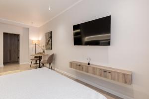 a bedroom with a bed and a tv on a wall at The First Apart Hotel in Almaty