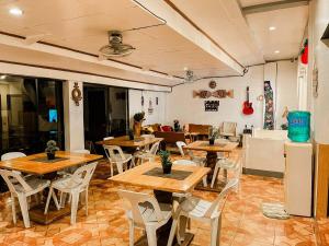 a restaurant with wooden tables and white chairs at Mario's Travellers Inn in Coron