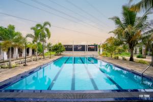 a swimming pool with palm trees in front of a building at Riverside Hotel Colombo in Katunayaka