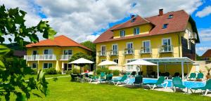 a large yellow building with chairs and a swimming pool at Dorf Hotel Grüner Baum in Maria Laach am Jauerling