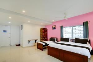 two beds in a room with a pink wall at Super Hotel O SRI NIRVANA PLAZA in Gachibowli
