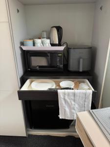 a small kitchen with a microwave and some dishes at Razak House in Brighton & Hove