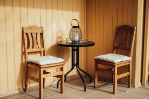 a small table with two chairs and a bird cage on it at Brakši Namiņš in Pērkone