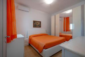 a bedroom with an orange bed and a bathroom at Villa Stellina and Trullo Cecé in Ostuni