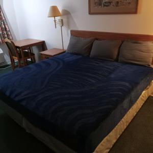a bed in a room with a blue blanket on it at King Bed Hotel Studio 232 in Livingston +6 photos