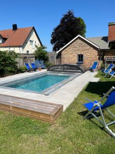 a swimming pool in a yard with chairs and a house at Windalens på Österlen in Tomelilla