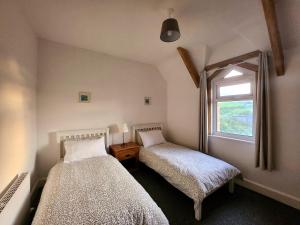 twee bedden in een kamer met een raam bij The Trackside Cottage in Carlin How