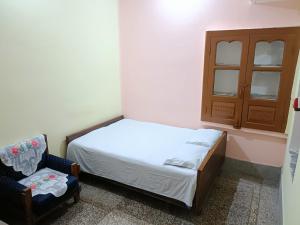 a small bedroom with a bed and a chair at Shanker Bhawan Homestay in Gaya