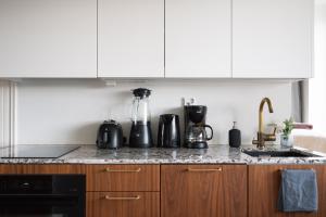una cucina con armadietti bianchi ed elettrodomestici neri di Comfy Top Floor Studio Apt in Centre of Helsinki a Helsinki