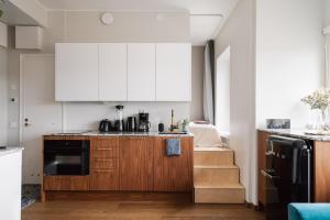 una cucina con armadietti bianchi e una scala di Comfy Top Floor Studio Apt in Centre of Helsinki a Helsinki