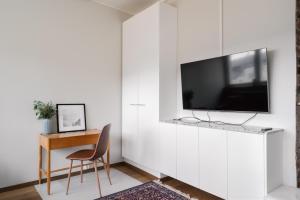 un soggiorno con TV su una parete bianca di Comfy Top Floor Studio Apt in Centre of Helsinki a Helsinki